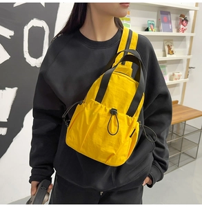 Detail view of a bright yellow nylon crossbody bag featuring adjustable straps and drawstring pocket