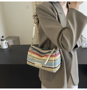 Detail of colorful striped woven cylinder bag with floral gold chain and leather strap
