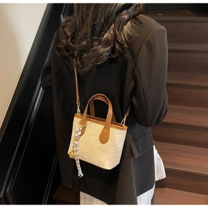Detail of cream bucket bag with star embossing and polka dot scarf accessory