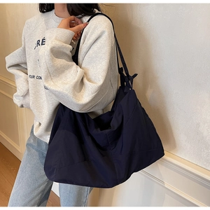 Deep blue nylon tote bag with wide shoulder strap and soft slouchy design for commuting