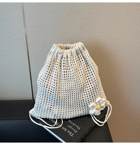 Detalle del bolso de crochet blanco con colgante de flor sobre un libro con textura