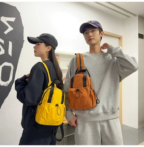 Close-up of lightweight nylon mini backpacks in yellow and orange with drawstring pockets