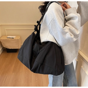 Close-up of a large black minimalist tote bag showing matte fabric texture and spacious design