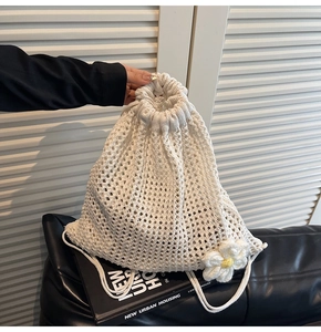 Detalle del bolso de cordón de ganchillo blanco calado con una pequeña flor de margarita