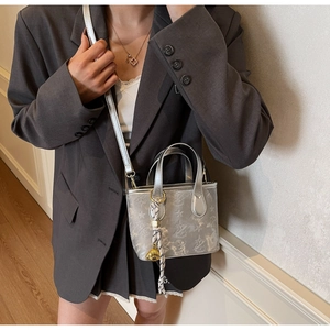 Detail of silver bucket bag with star patterns and woven rope charm accessory
