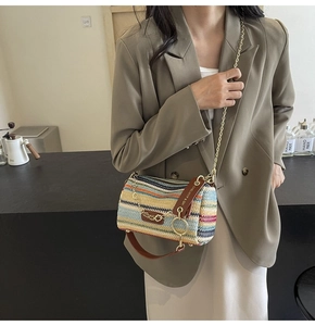 Detail of multi-color woven pillow bag with gold chain strap and leather handle