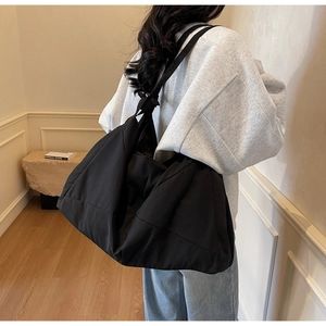 Large black minimalist nylon tote bag shown on shoulder for daily commute style