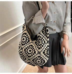 Detailed macro view of black and white hand-crocheted floral tote bag with woven texture
