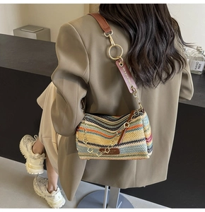 Detailed close-up of bohemian rainbow straw bucket bag with brown leather strap and gold ring