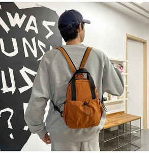 Detail of caramel nylon backpack featuring drawstring pockets and waterproof fabric texture
