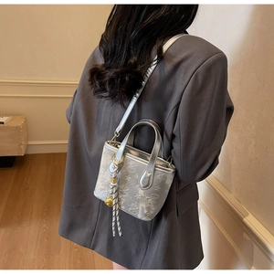 Detail of silver bucket bag with angel relief pattern and braided rope knot charm