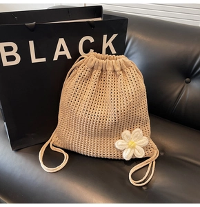 Detalle de bolsa de paja tejida beige con cordón ajustable y margaritas blancas