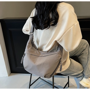 Detail of grey hobo dumpling bag showing multiple zipper pockets and woven rope pulls