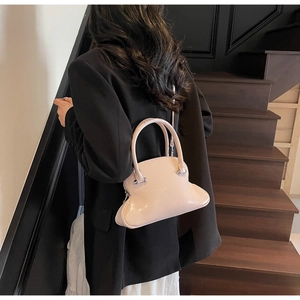 Pink niche designer shell handbag shown in a street style fashion setting on wooden stairs