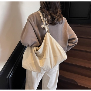 Detail showing beige canvas tote bag with large capacity and stylish shoulder knot detail