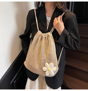 Détail de la texture crochetée et fleur de marguerite 3D sur un sac beige à cordon