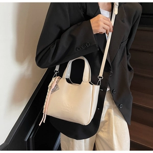 Dettaglio della borsa a secchiello bianco sporco con logo a rilievo e foulard di seta