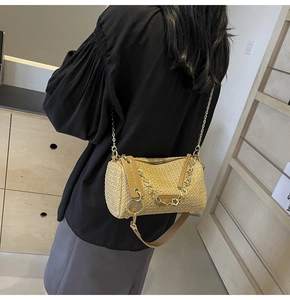 Chic beige woven cylinder bag with brown leather strap and gold chain shown on shoulder
