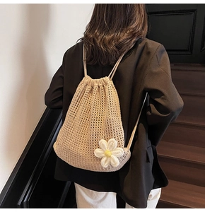 Détail macro d'un sac à dos en crochet beige avec un petit accessoire de marguerite blanche