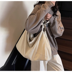 Spacious off-white canvas tote bag with a wide shoulder strap and soft pleat design