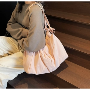 Detail of light pink canvas tote bag featuring a decorative knotted shoulder strap