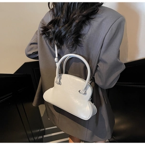 Detail of elegant cream shell handbag with glossy finish and cylindrical handle for women