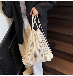 Detalle de bolso de ganchillo blanco hecho a mano con una margarita tejida decorativa
