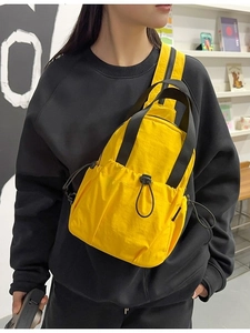 Lightweight bright yellow nylon crossbody bag with drawstring pocket and black straps
