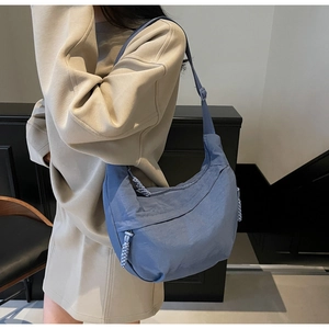 Close-up of blue crescent dumpling bag with pleated nylon fabric and braided zipper pull