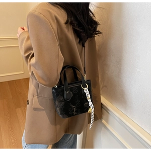 Detail of black mini bucket bag with butterfly pattern and striped scarf accessory