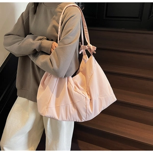 Detail of pink quilted tote bag with decorative bow handles on stylish commuter shoulder bag