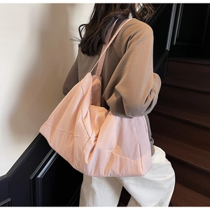 Rear view of a model carrying a large pink quilted tote bag on dark wooden stairs
