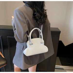 Detail shot of light blue cloud-shaped crossbody bag worn by a model in a gray suit