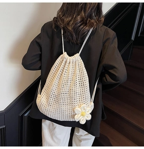 Detalle de la mochila de malla de ganchillo blanca con amuleto de margarita y cordón