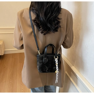 Detail of black leather bucket bag featuring star print and striped silk scarf on handle