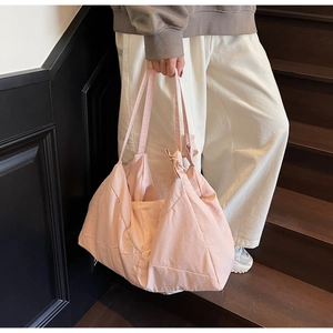 Detail of light pink tote bag featuring a soft fabric texture and knotted strap design