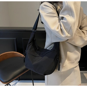 Detail view of black crescent crossbody bag showing fabric texture and adjustable shoulder strap