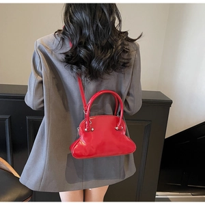 Red glossy shell bag shown on model wearing grey suit for visual color contrast