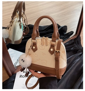 Detail of shell-shaped crossbody bag with embossed animal motifs and plush pompom charm