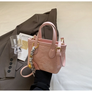 Detail of pink embossed bucket bag featuring elegant floral texture and gold hardware