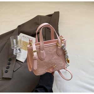 Detail of pink PU leather bucket bag with star and floral embossing and woven charm