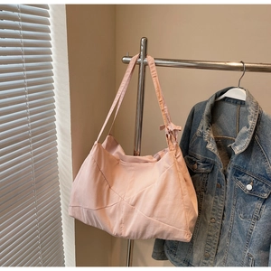 Detail of light pink tote bag with geometric stitching and ribbon bow on clothing rack