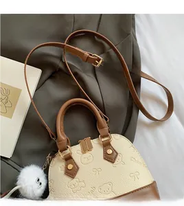 Detail of minimalist shell bag with lychee texture, adjustable strap and plush charm
