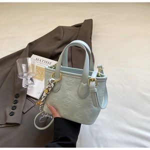 Close-up of mint blue embossed handbag with decorative scarf and gold hardware