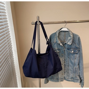Close-up of a large navy blue hobo tote bag with geometric stitching on a metal hanger