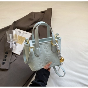Detail of light blue embossed bucket bag with gold hardware and decorative scarf