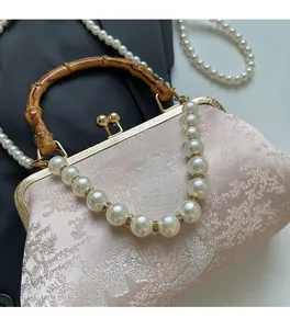 Detail der rosa Jacquard-Stofftasche mit Naturbambusgriff und feinen Perlenakzenten