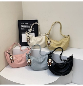 Detail view of crescent shoulder bags in five colors with cute bear charms on stands