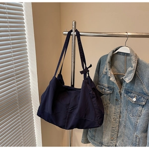 Detail of navy blue quilted tote bag with unique knot strap hanging on a metal hanger