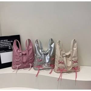 Three stylish shoulder tote bags with decorative side bows in pink, silver, and beige